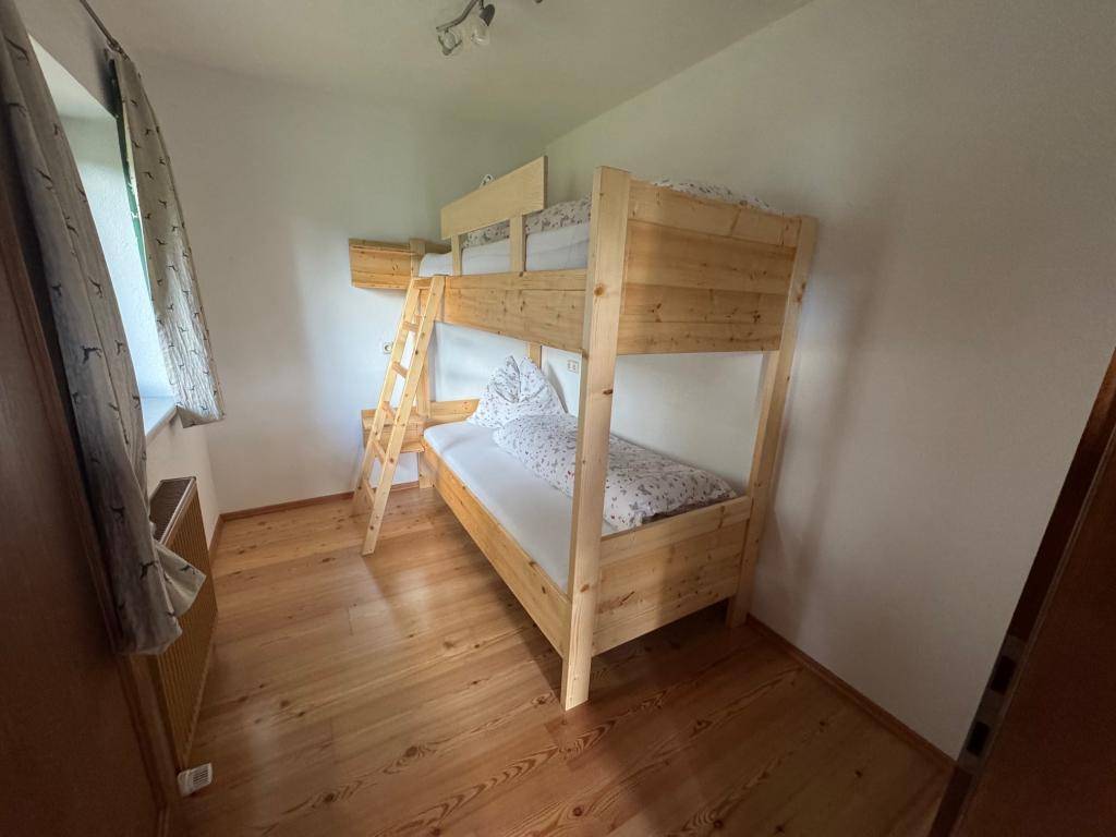 Gemütliches Schlafzimmer mit Etagenbett aus hellem Holz und Holzboden, ideal für Kinder oder Gäste.