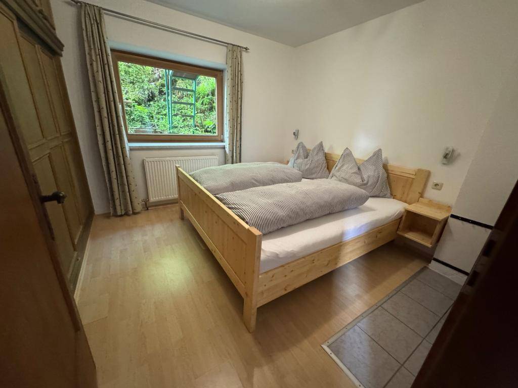 Schlafzimmer mit Doppelbett aus hellem Holz, Holzboden und Fenster mit Blick auf die Natur.