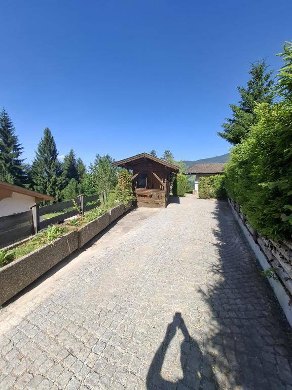 Lange gepflasterte Einfahrt, gesäumt von Blumenbeeten und Hecken, führt zum Anwesen unter blauem Himmel.