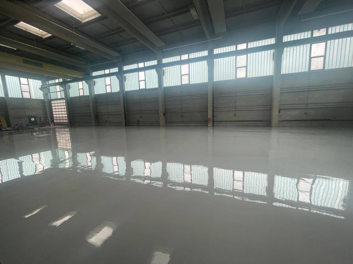 Weitläufige Industriehalle mit glänzendem Boden, hohen Decken und zahlreichen Fenstern für optimale Beleuchtung.