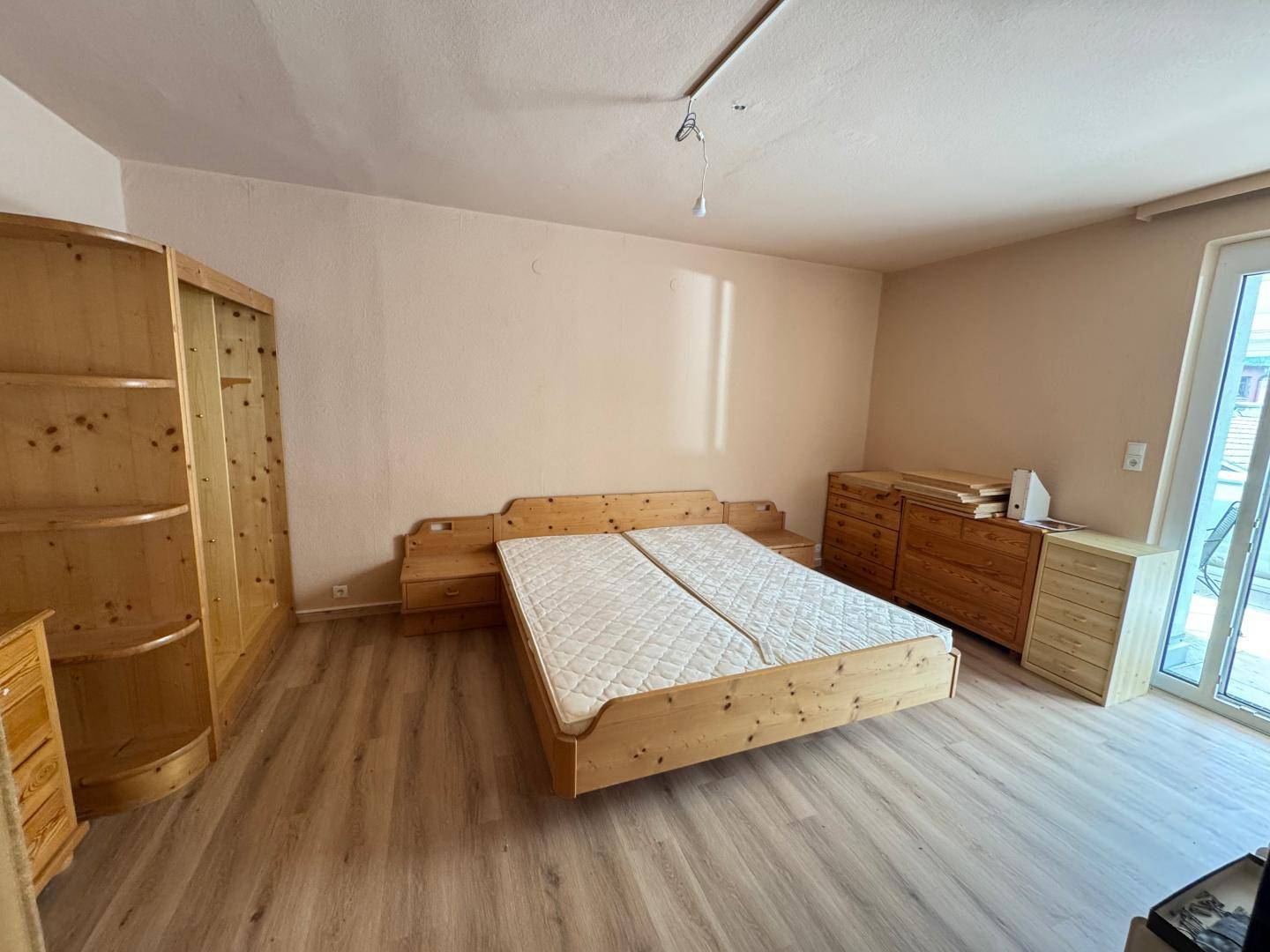 Schlafzimmer mit Holzmöbeln, Parkettboden und Zugang zu einem Außenbereich.