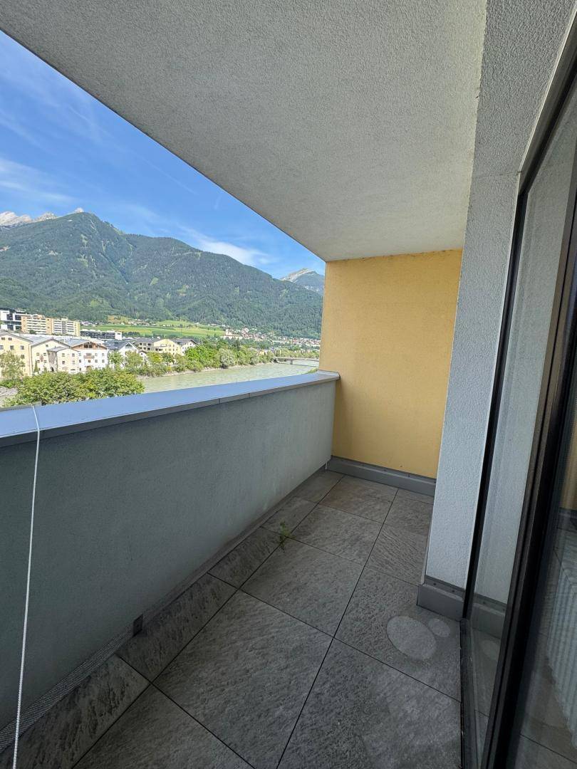Balkon mit Fliesenboden und weitem Blick auf den Fluss und die Berge.