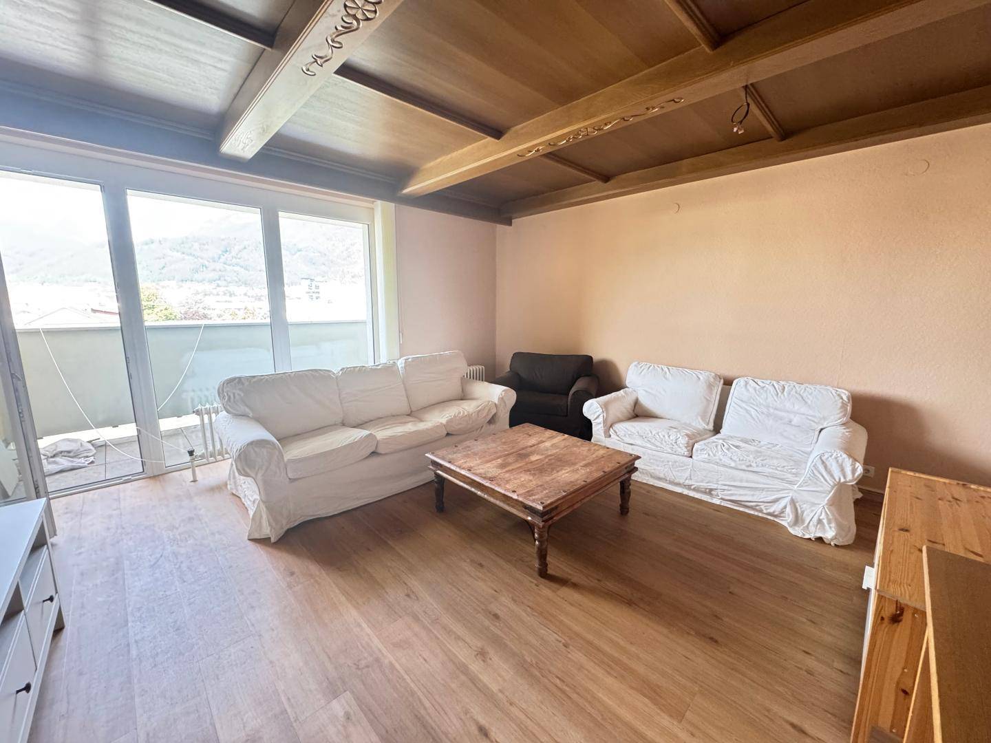Helles Wohnzimmer mit Holzboden, bequemen Sofas und Zugang zum Balkon.