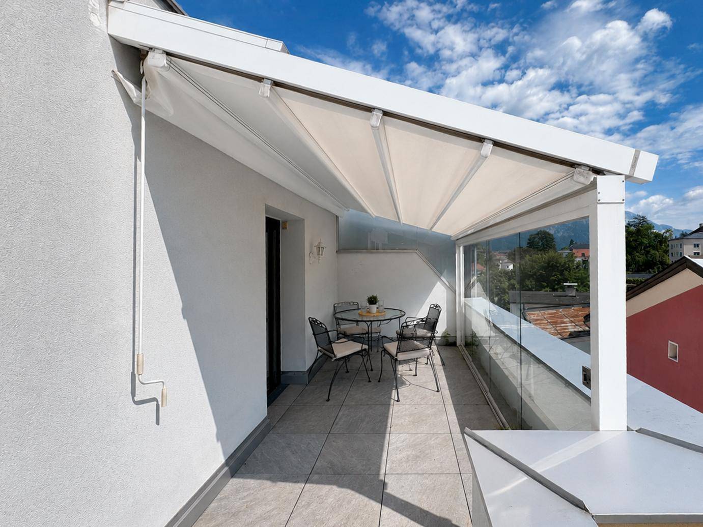 Überdachte Terrasse mit Glasgeländer und Blick auf die umliegende Landschaft.