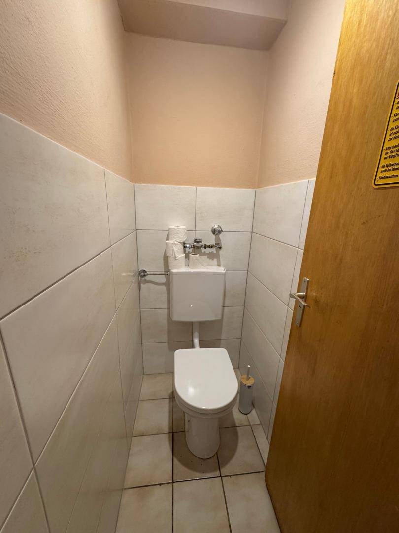 Kleines Gäste-WC mit weißer Toilette und hellen Fliesen an den Wänden.