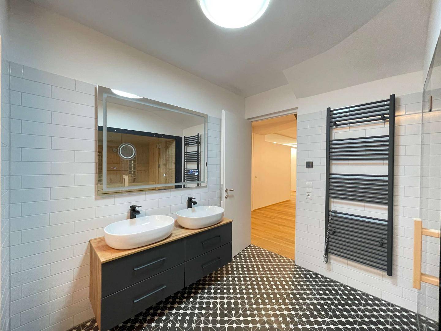 Modernes Badezimmer mit Doppelwaschbecken, großem Spiegel und beheiztem Handtuchhalter.