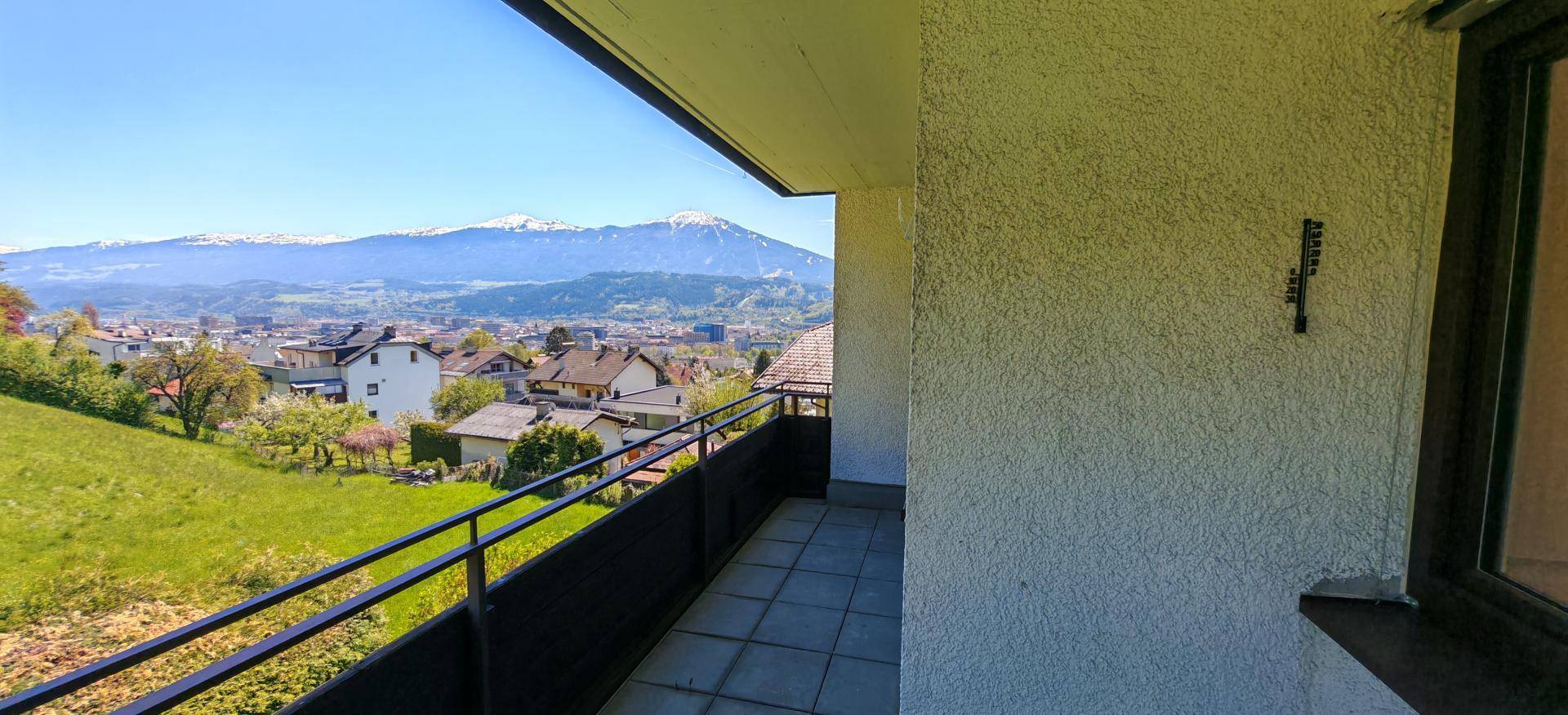 Balkon mit Fliesenboden und weitem Blick über die grüne Landschaft und die Stadt.