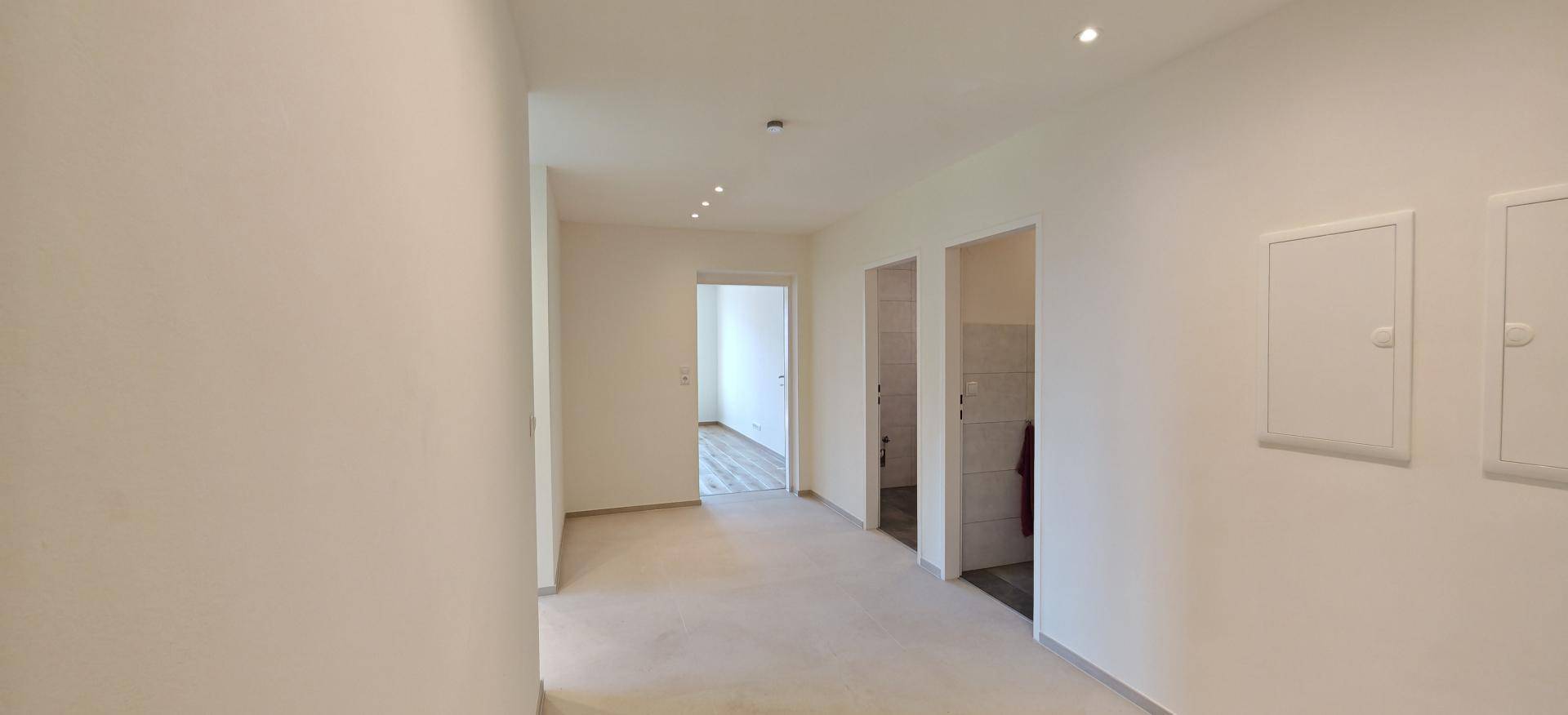 Heller Flur mit Fliesenboden und Zugang zu verschiedenen Räumen der Wohnung.