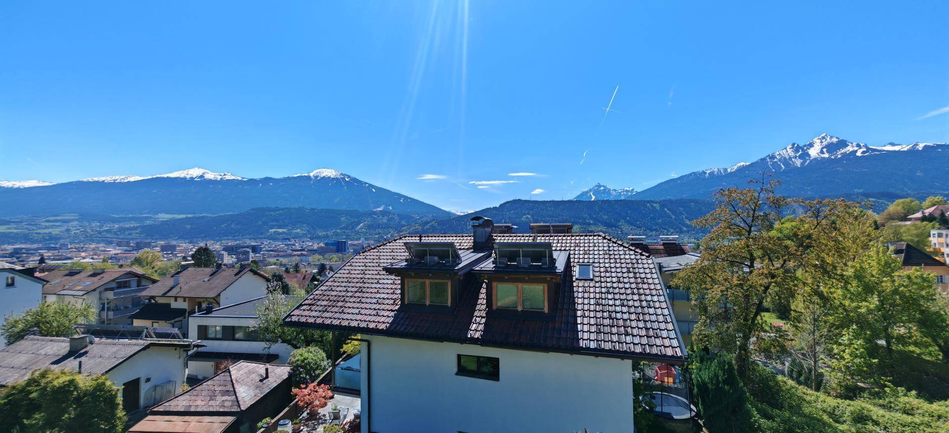 Panoramablick auf die Stadt und die schneebedeckten Berge unter strahlend blauem Himmel.