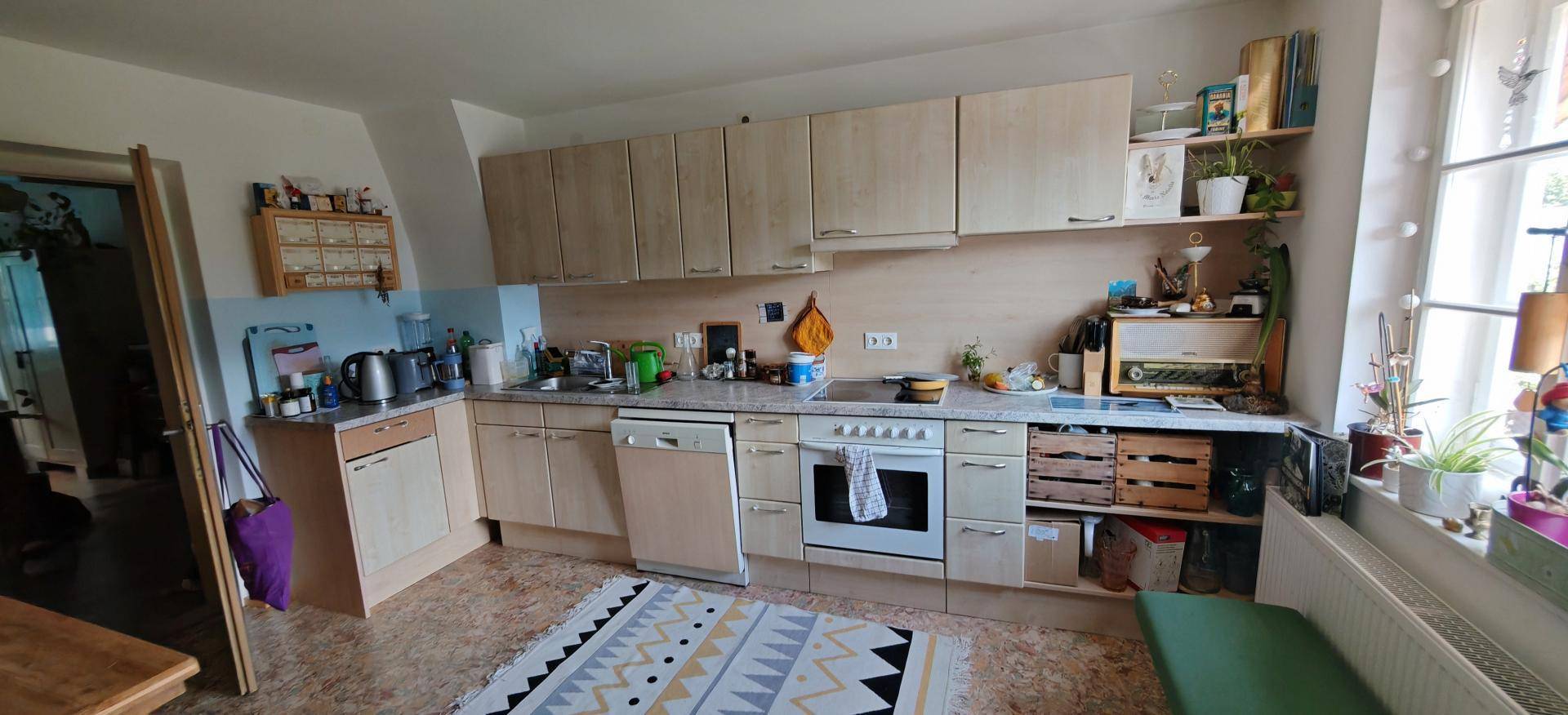Funktionale Einbauküche mit hellen Schränken, modernen Geräten und einem Fenster für natürliches Licht.