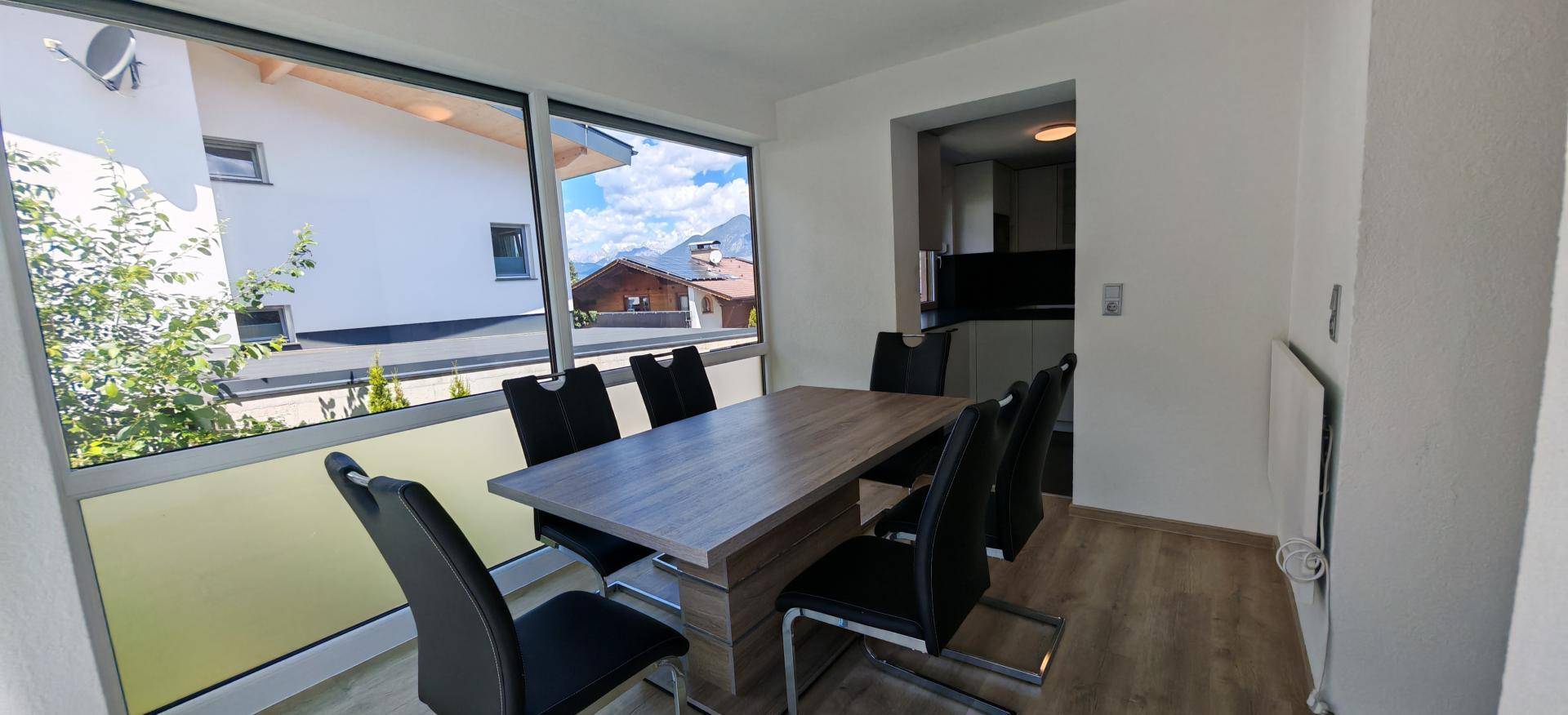 Heller Essbereich mit Holztisch und großen Fenstern, die einen weiten Blick bieten.
