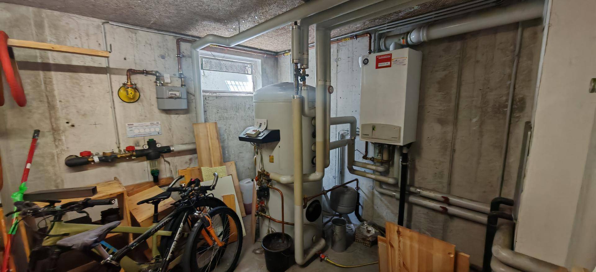 Technikraum im Keller mit Heizungsanlage, Leitungen und Abstellmöglichkeiten.