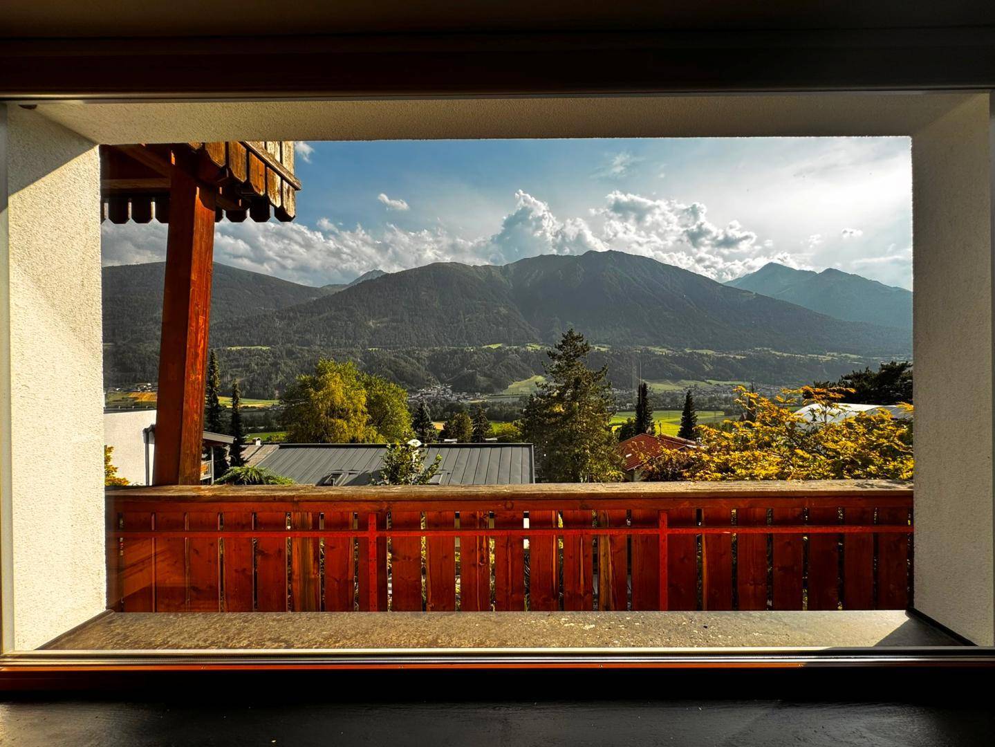 Malerischer Ausblick durch ein Fenster auf die bewaldeten Berge und das Tal.