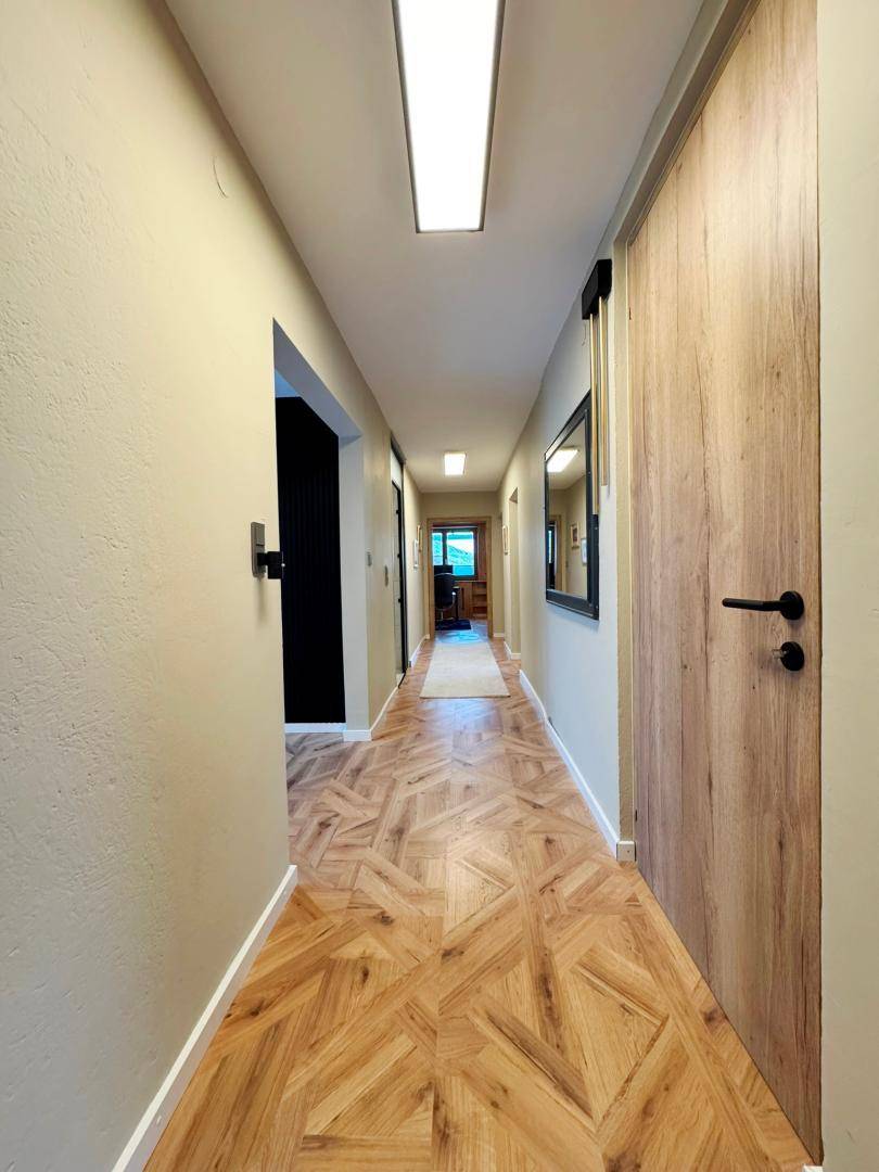 Heller Flur mit modernem Holzboden und schlichten Holztüren.