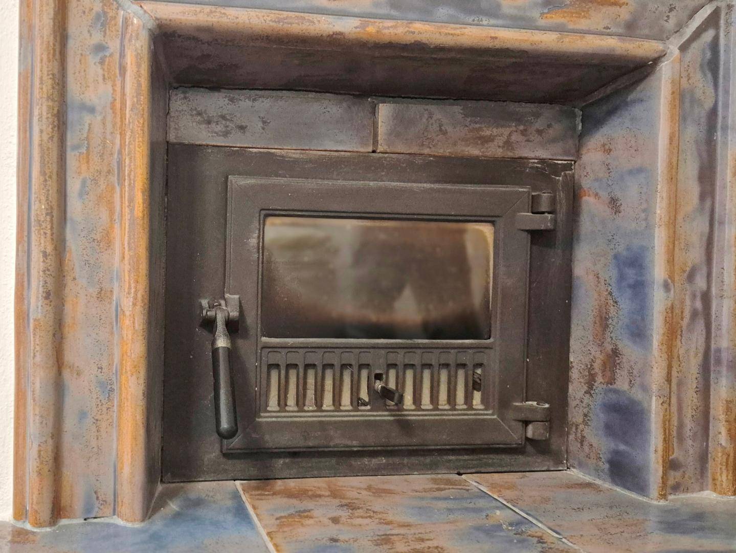 Nahaufnahme eines traditionellen Kaminofens mit verzierter Metalltür.
