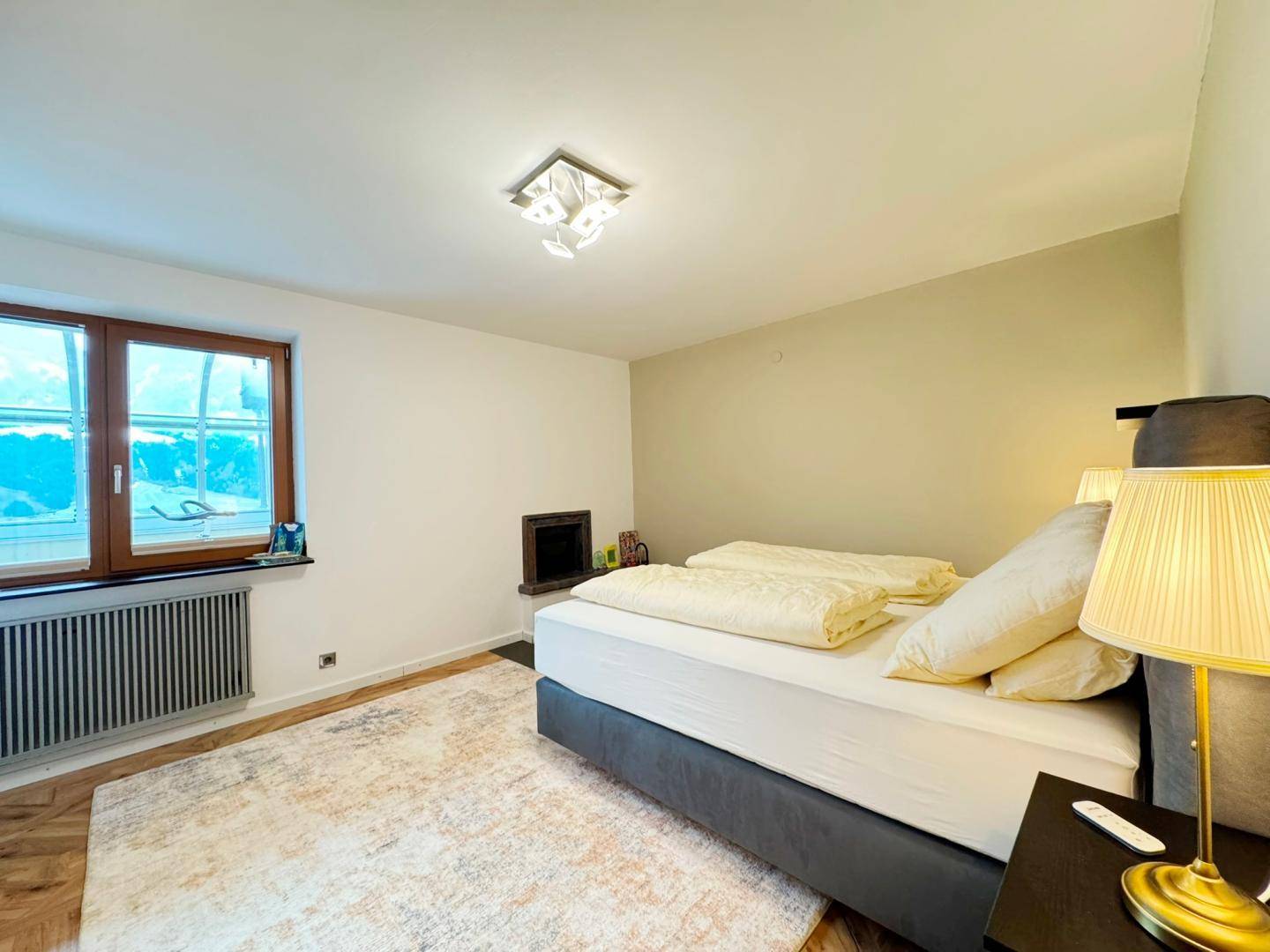 Schlafzimmer mit Doppelbett, Teppich und einem integrierten Kaminofen.