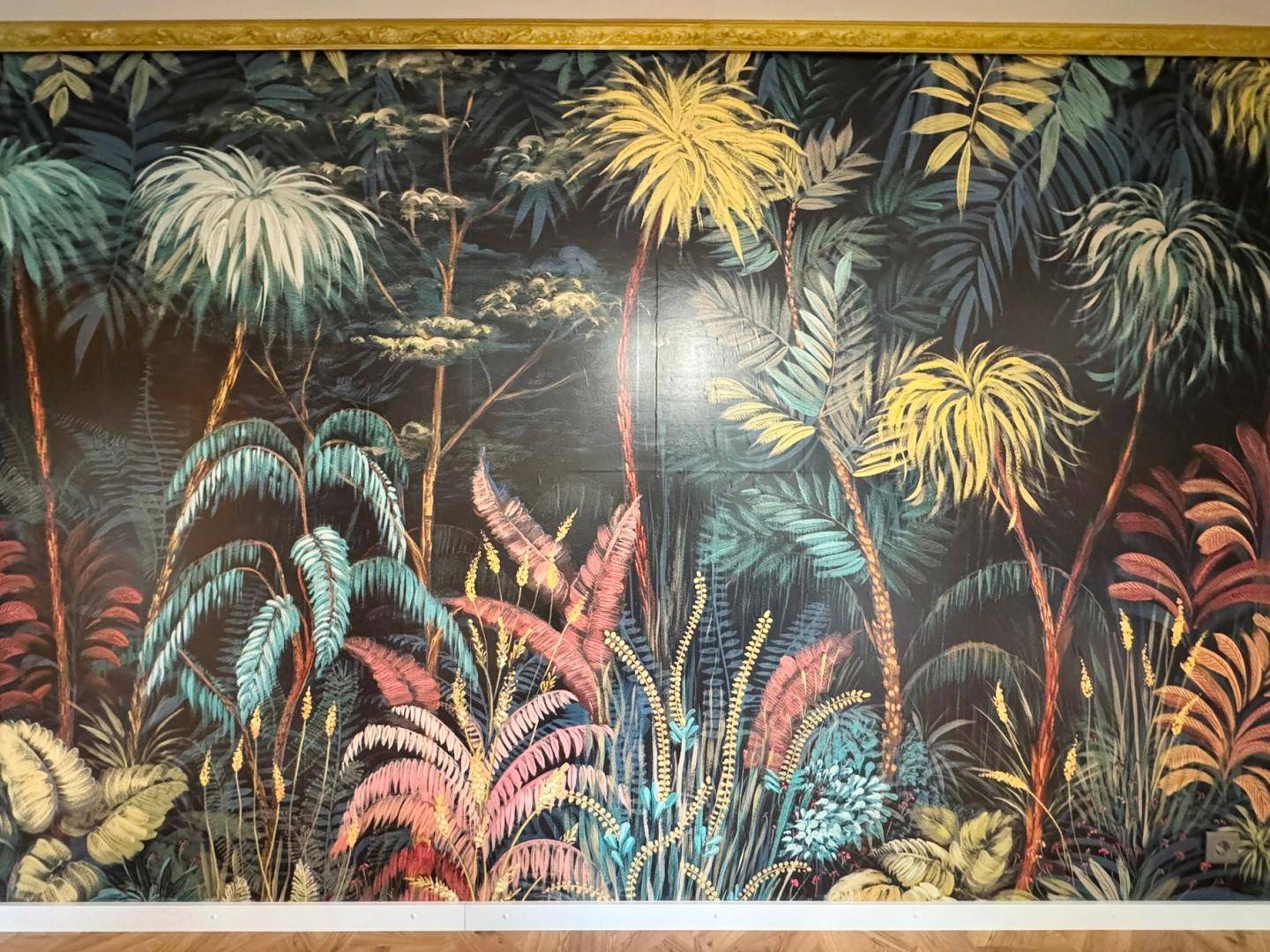 Detailaufnahme einer farbenfrohen Tapete mit exotischen Pflanzen und Palmenmotiven.