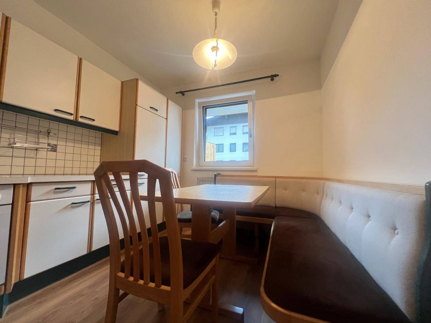 Gemütliche Einbauküche mit Essbereich, Fenster und traditionellen Holzmöbeln.