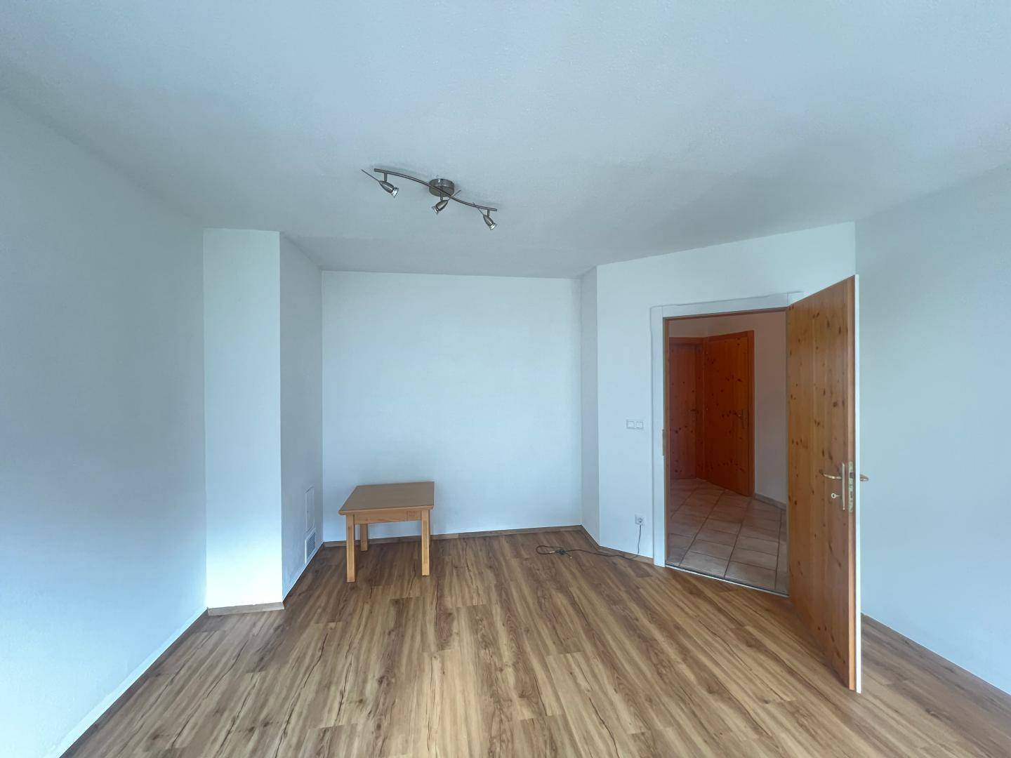 Geräumiges Zimmer mit Laminatboden und weiß gestrichenen Wänden, ideal als Wohnbereich.