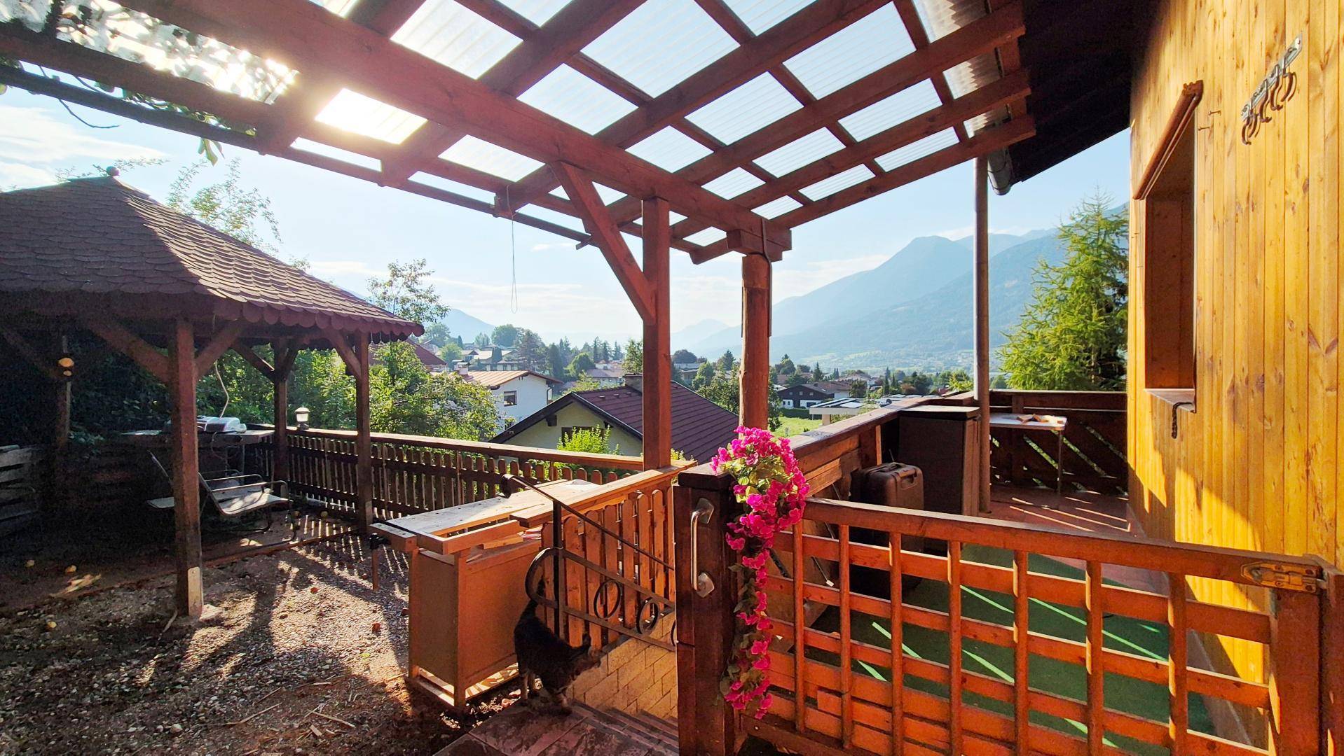Große Holzterrasse mit Pergola und atemberaubendem Bergblick, ideal für Entspannung.