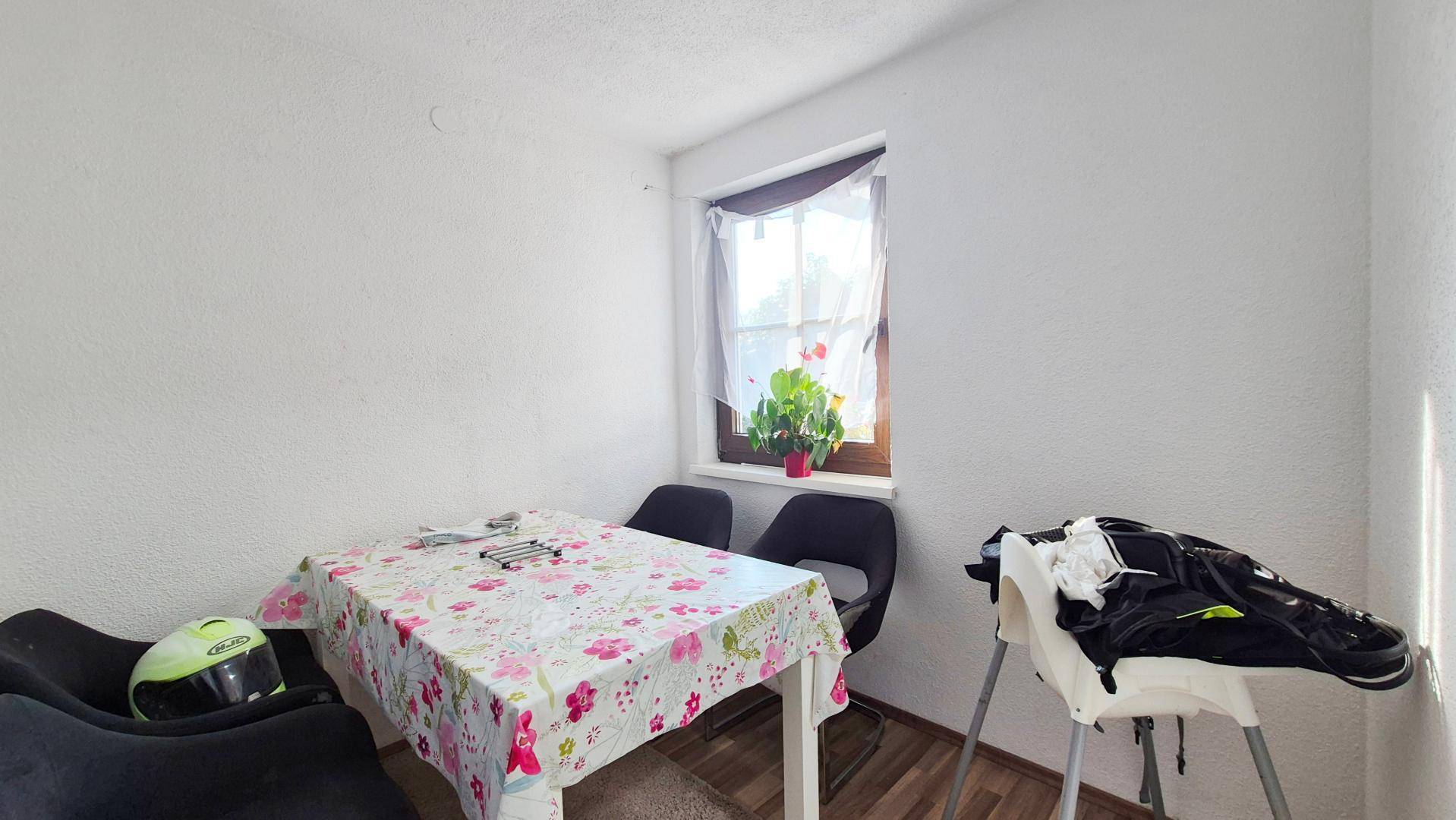 Kleiner Essbereich mit einem Tisch, Stühlen und einem Fenster, das Tageslicht hereinlässt.