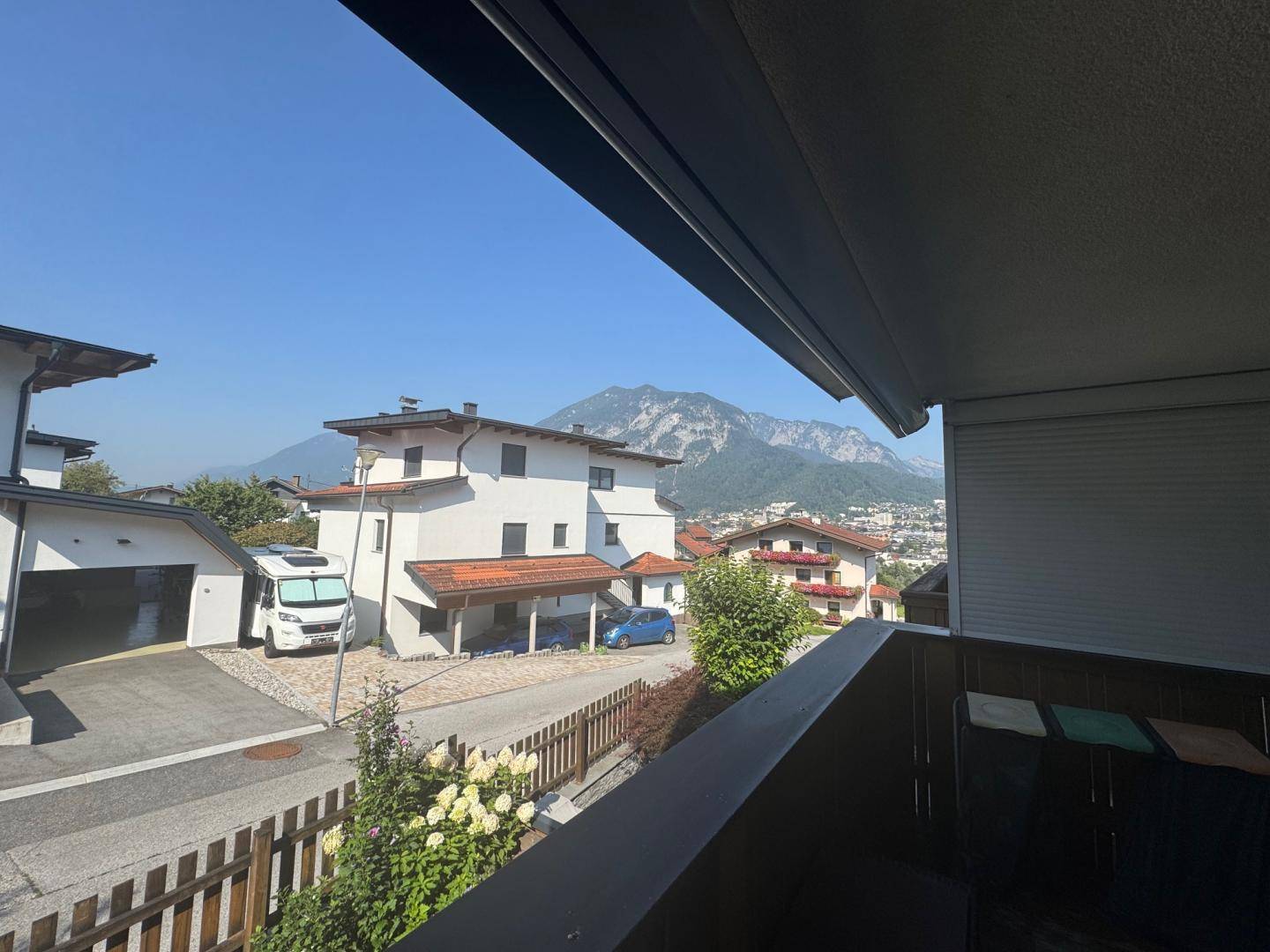 Panoramablick vom Balkon auf die umliegenden Häuser und die majestätischen Berge.