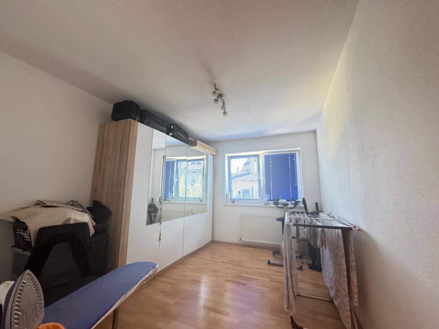 Praktischer Raum mit Schrank, Bügelbrett und Tageslicht, vielseitig nutzbar.