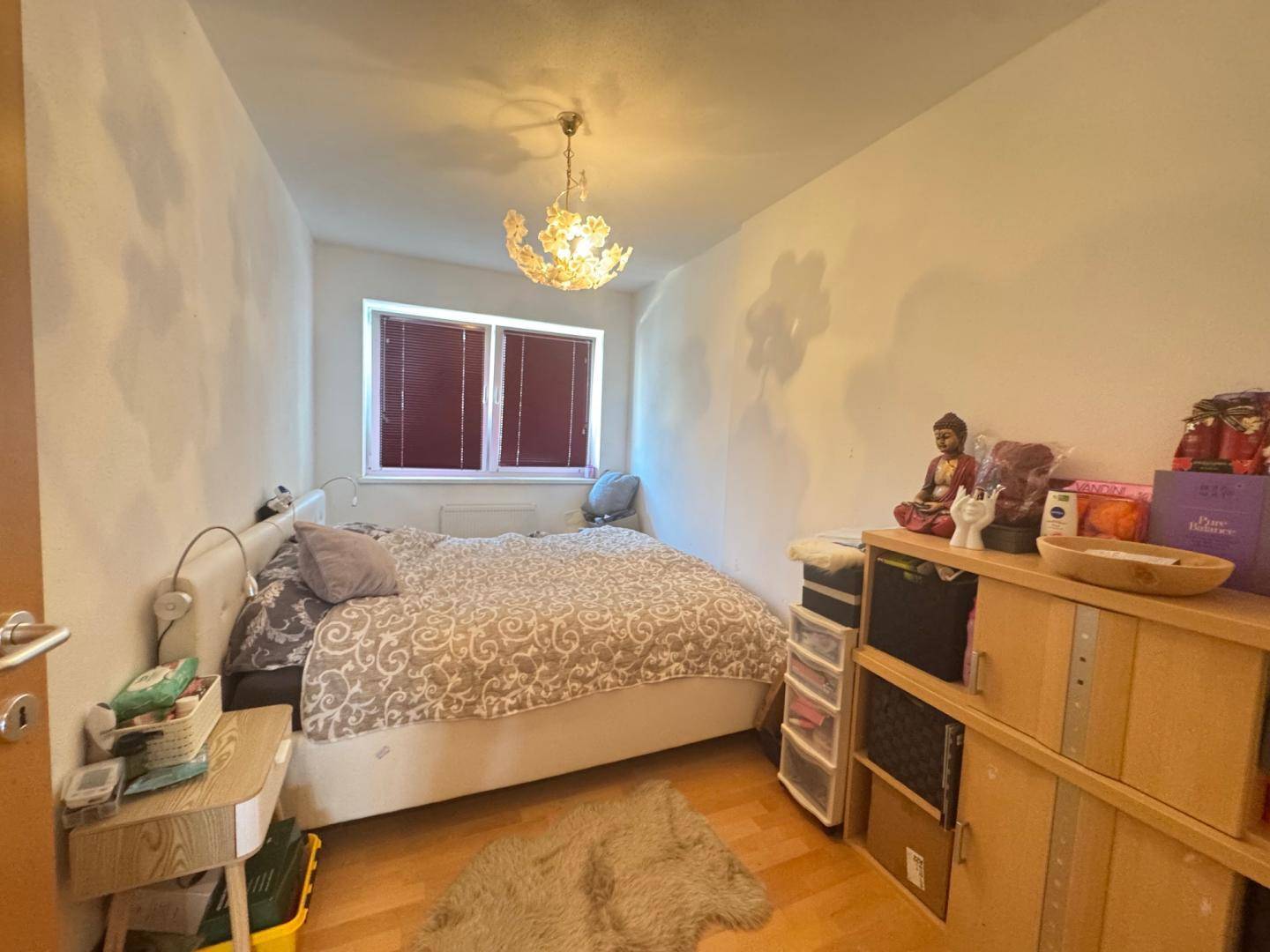 Gemütliches Schlafzimmer mit Doppelbett, Holzboden und einem auffälligen Kronleuchter.