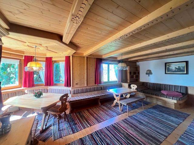 Gemütlicher Wohn-Essbereich im alpinen Stil mit Holzbalkendecke und traditionellen Sitzgelegenheiten.