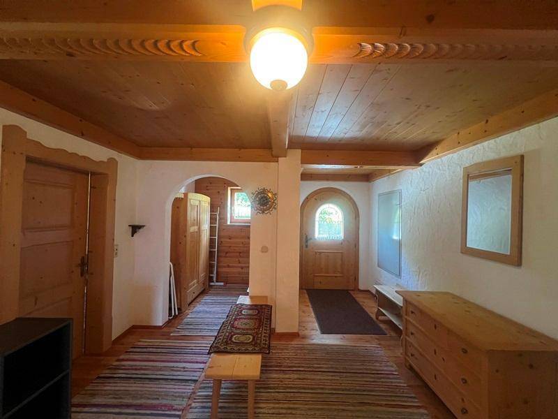 Heller Eingangsbereich mit Holzbalkendecke, weiß getünchten Wänden und rustikalen Möbeln.