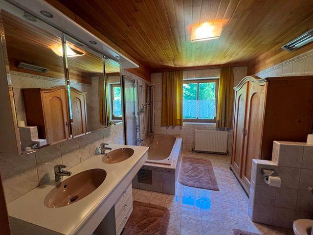 Geräumiges Badezimmer mit Doppelwaschbecken, Badewanne, Dusche und hellen Fliesen.