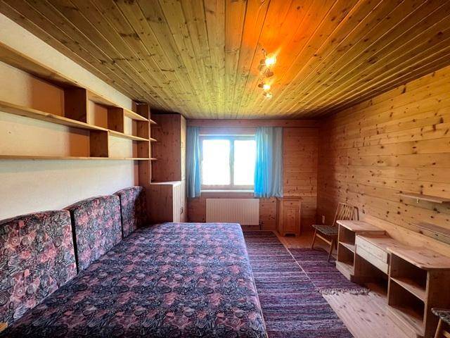 Schlafzimmer im Landhausstil mit Holzvertäfelung, eingebauten Regalen und einem Schlafsofa.