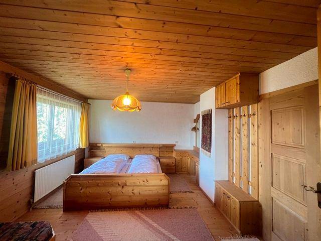 Helles Schlafzimmer mit Holzvertäfelung, Doppelbett und integrierten Holzmöbeln.