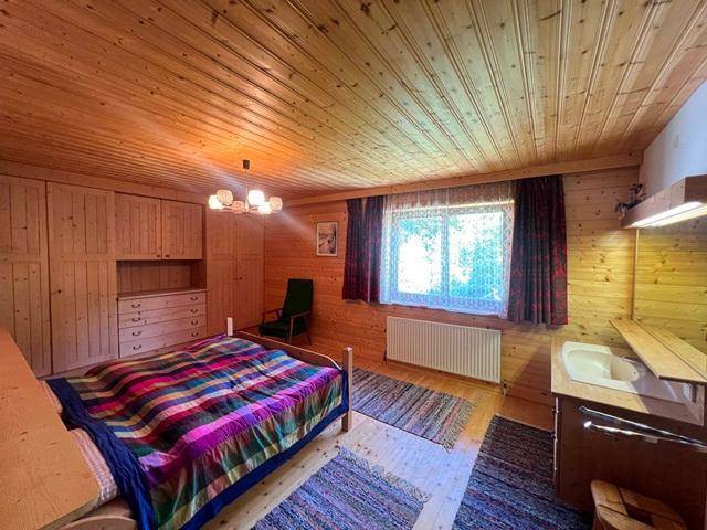 Rustikales Schlafzimmer mit Holzvertäfelung, Doppelbett und einem kleinen Waschbecken.
