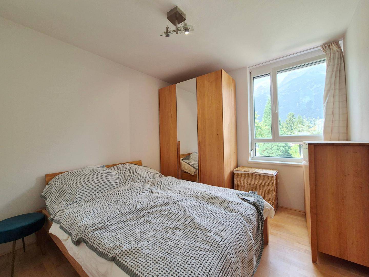 Schlafzimmer mit Holzbett, Spiegelschrank und einem Fenster, das einen schönen Bergblick bietet.