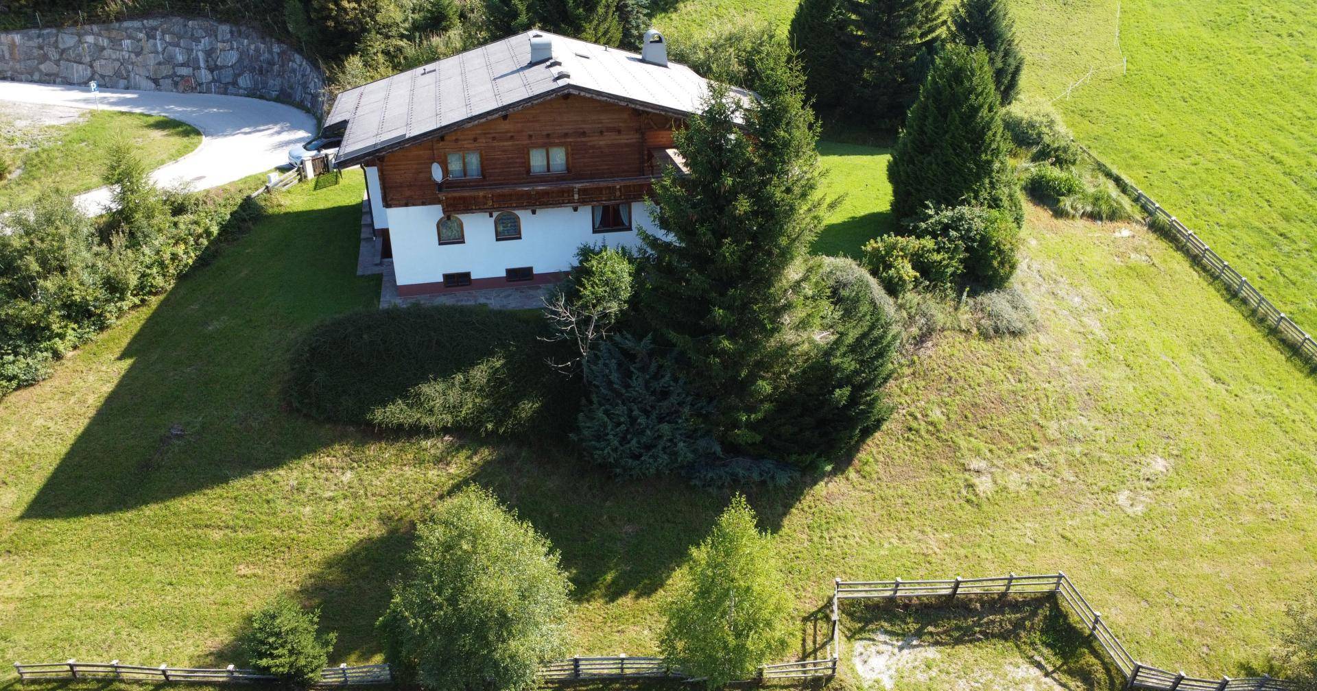 Weitläufige Luftaufnahme des Hauses mit großem Grundstück und grüner Hügellandschaft.