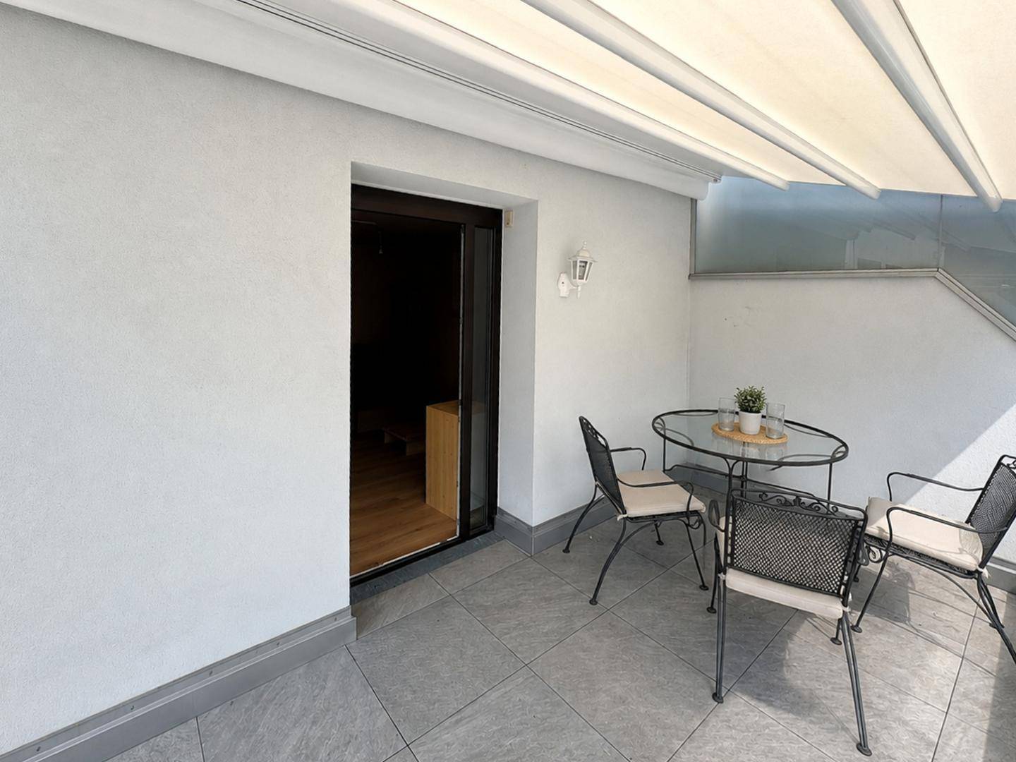 Detailansicht der Terrasse mit Zugang zum Innenbereich und modernen Fliesenboden.