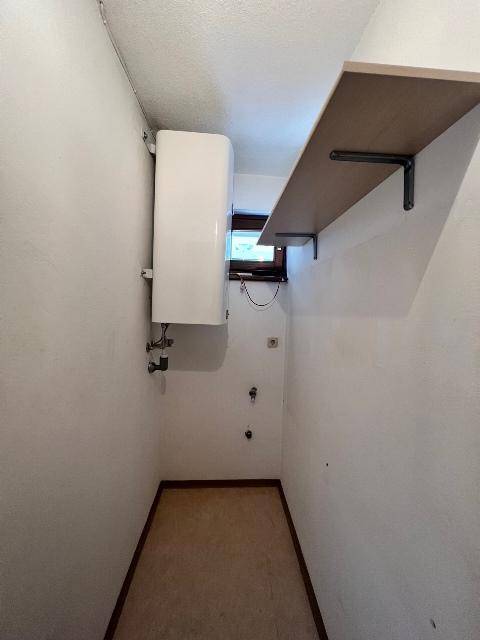 Praktischer Hauswirtschaftsraum mit Warmwasserbereiter, kleinem Fenster und einer Ablagefläche.