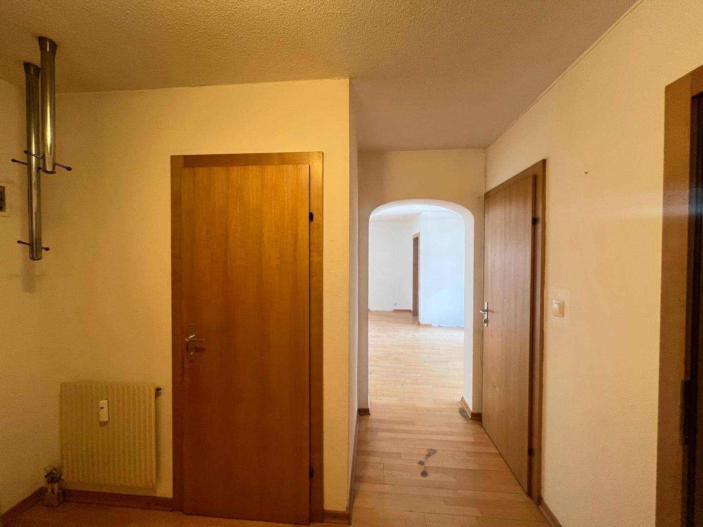 Flur mit Holztüren, Garderobe und einem Durchgang zu weiteren Räumen der Wohnung.