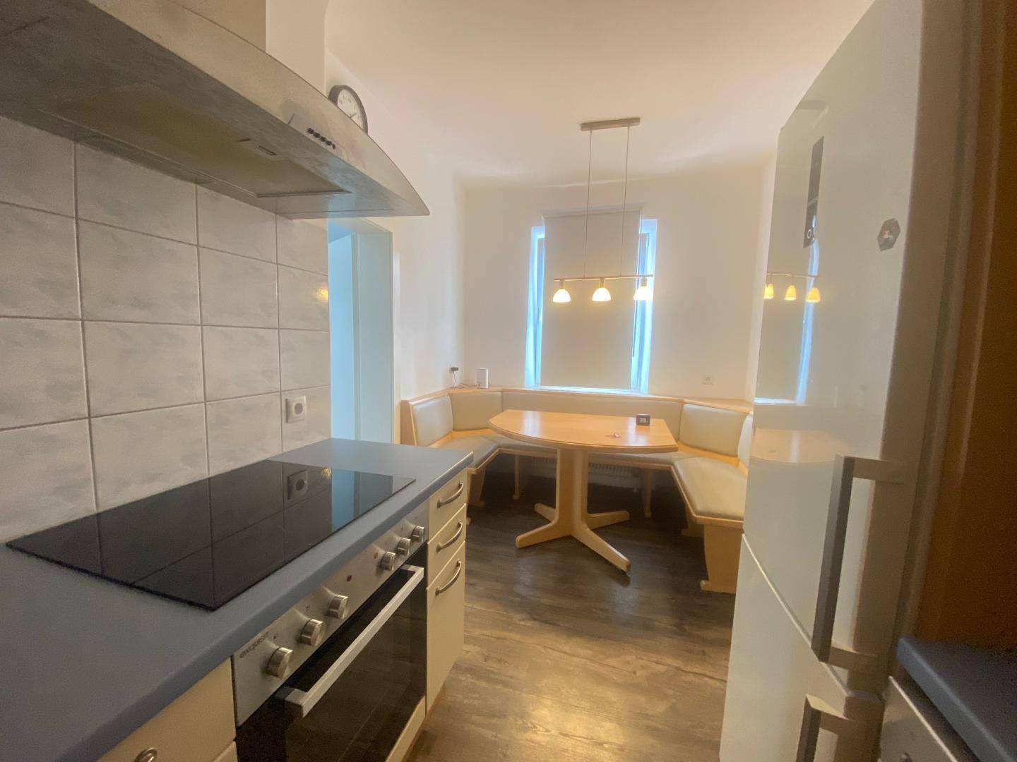 Gemütliche Wohnküche mit integrierter Essecke, Holztisch und Fenster für Tageslicht.