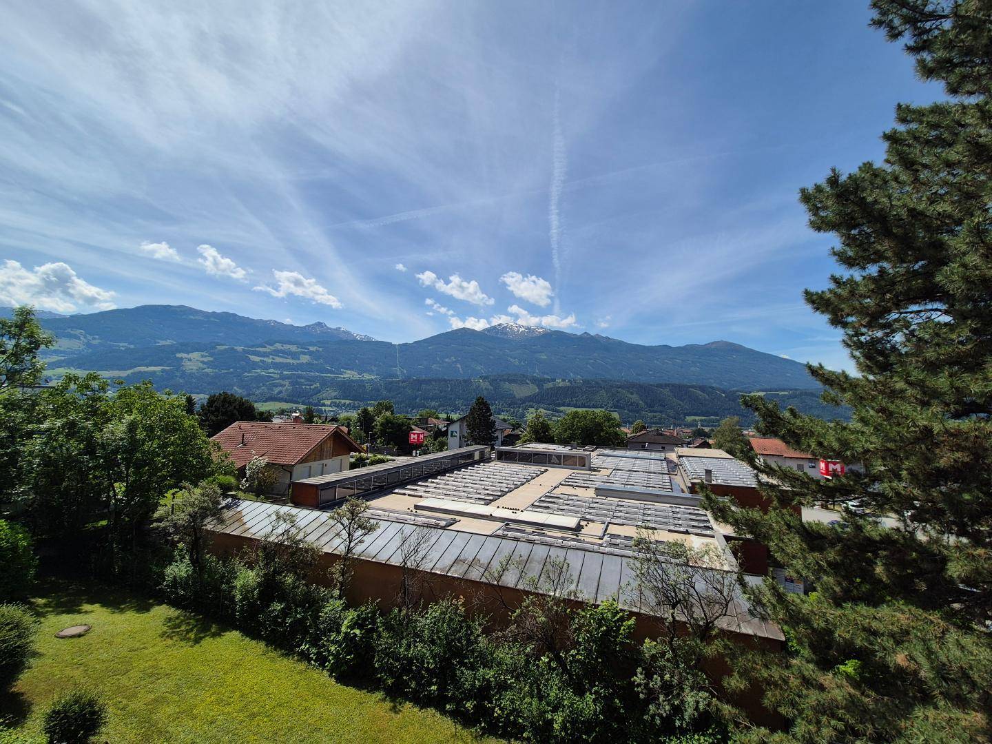 Weitläufiger Blick auf die majestätische Berglandschaft und die grüne Umgebung unter blauem Himmel.