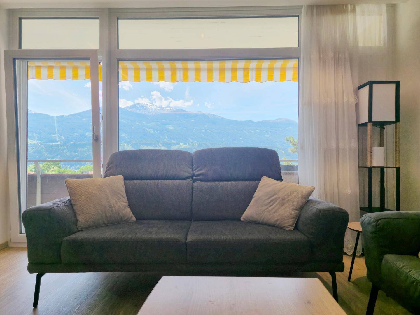 Komfortables Sofa im Wohnzimmer mit großem Fenster, das einen beeindruckenden Blick auf die Berge bietet.