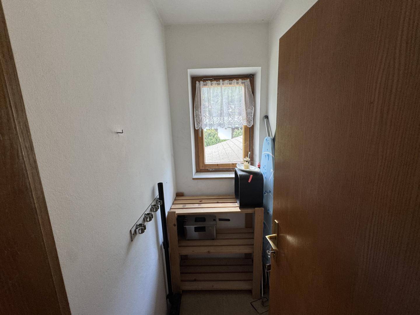 Kleiner Abstellraum mit Fenster, Regalen und Platz für Haushaltsgeräte.
