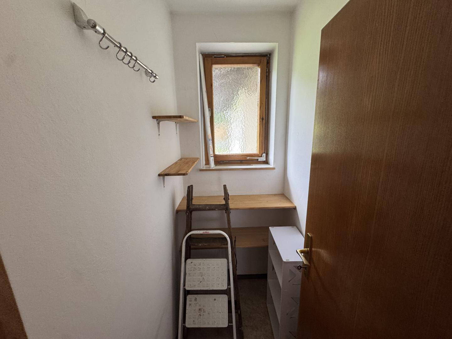 Kleiner Abstellraum mit Regalen, Fenster und Leiter für zusätzlichen Stauraum.