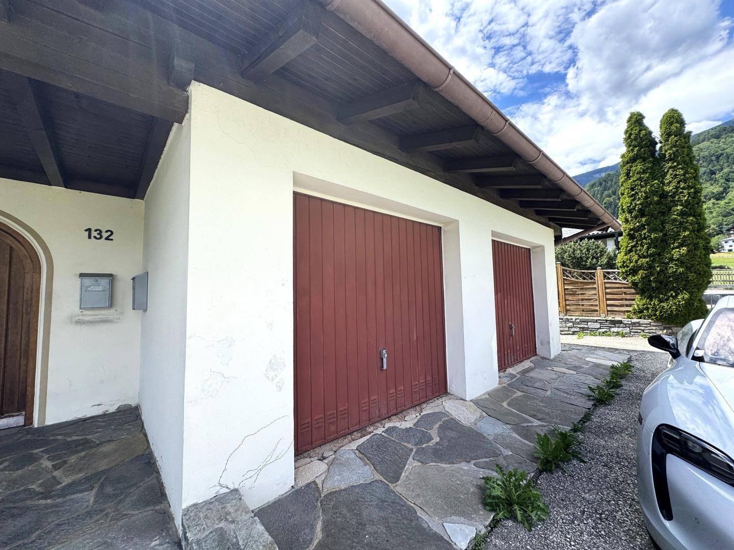 Doppelgarage mit Holztoren und gepflastertem Eingangsbereich des Hauses.