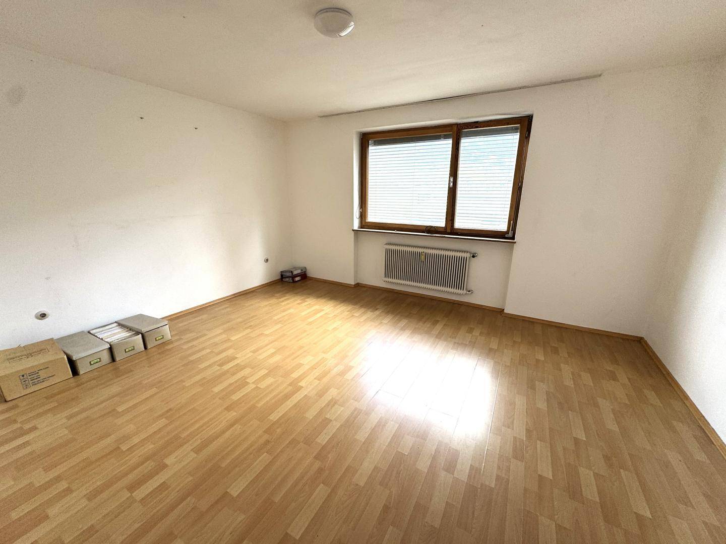 Geräumiges, helles Schlafzimmer mit Parkettboden und großem Fenster.