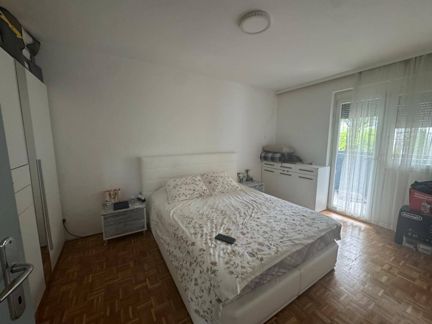 Schlafzimmer mit Doppelbett, weißem Kleiderschrank und Zugang zum Balkon, bietet viel Komfort.