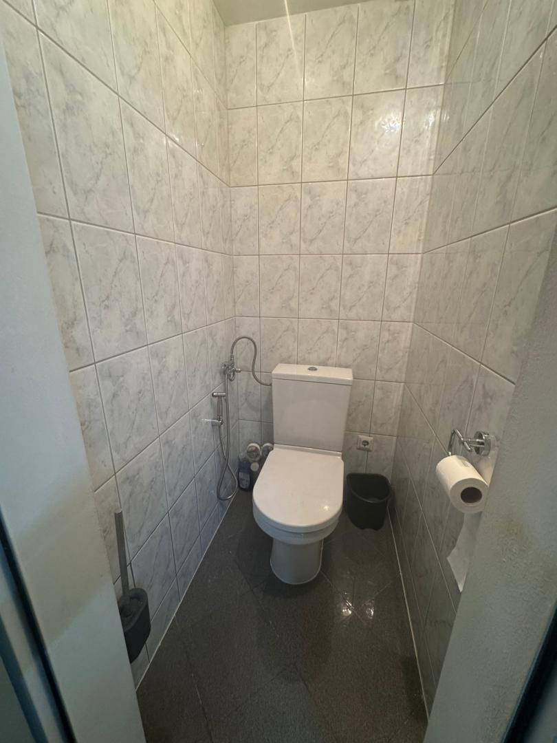 Separates WC mit hellen Wandfliesen und dunklem Boden, sauber und funktional gestaltet.