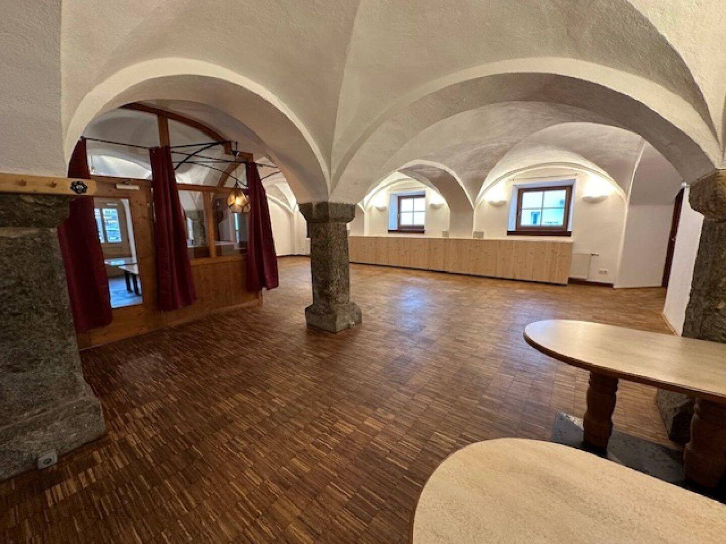Heller Gewerberaum mit Holzboden, Gewölbedecken und mehreren Fenstern, die für natürliche Belichtung sorgen.