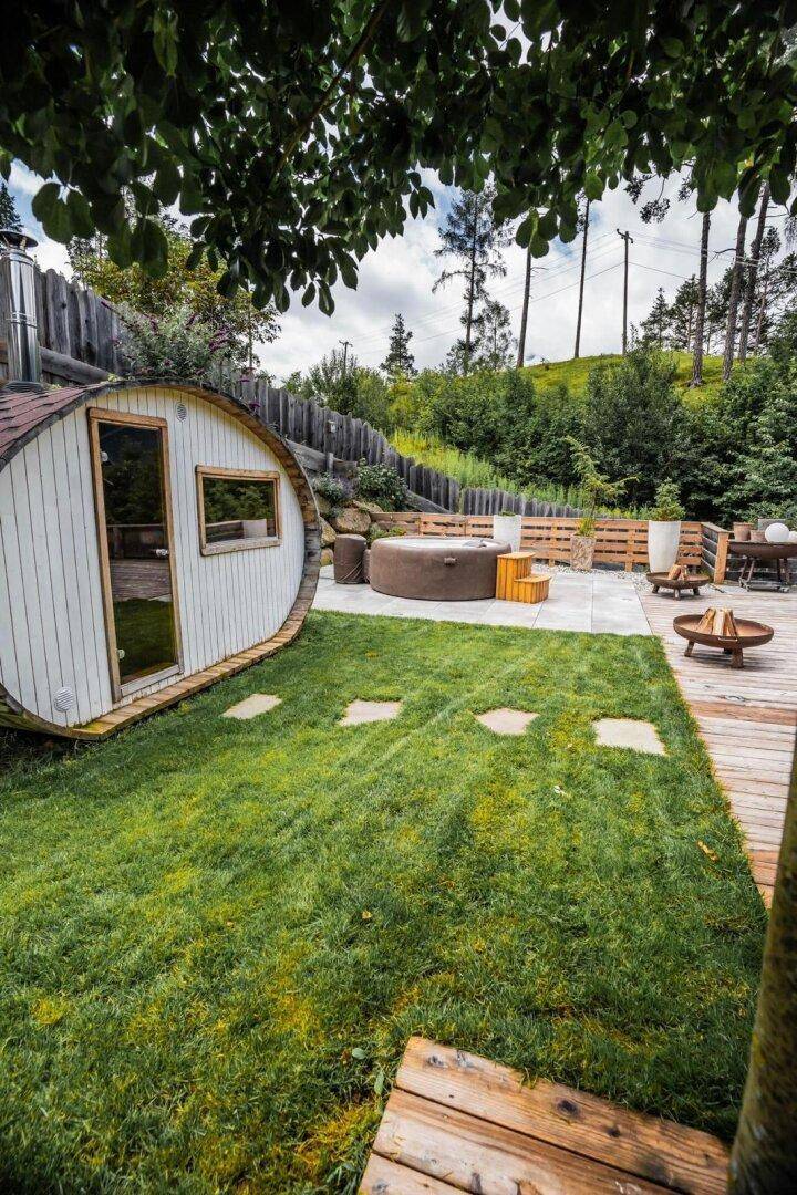 Gemütlicher Gartenbereich mit Fasssauna, Whirlpool und Holzterrasse.